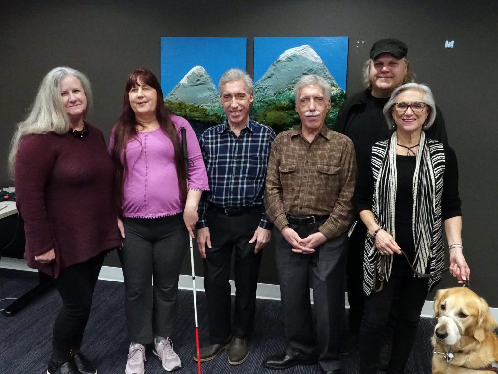 The group of artists standing in front of the pieces of art 