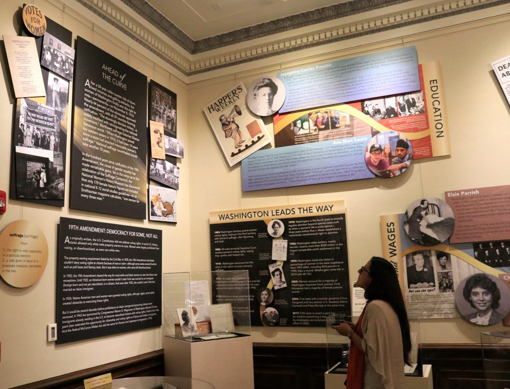 In September 2019, Legacy Washington opened its in-person and online Ahead of the Curve exhibit, which in 2020 celebrated the 100th anniversary of American women gaining the right to vote. A visitor to the Legislative Building in Olympia is reading the display panels that tell stories about some of Washington’s most amazing women (Photo: Legacy Washington).