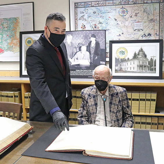 Washington Secretary of State Steve Hobbs (left) pointing to a page of the original Washington State Constitution with Frank Porter Hungate.