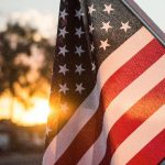 The United States flag with the setting sun for backlight.